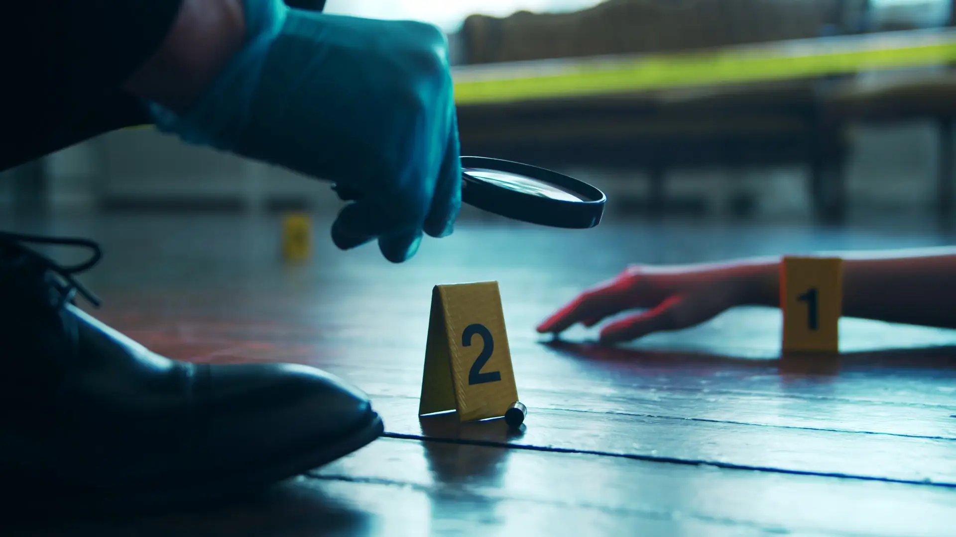 crime scene investigator holding a magnifying glass over a bullet shell casing